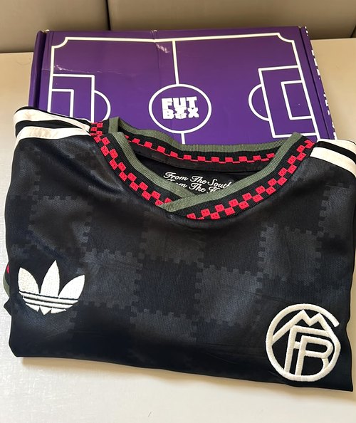 Caixa roxa da Futbox aberta com a camisa 3 preta do Bayern
